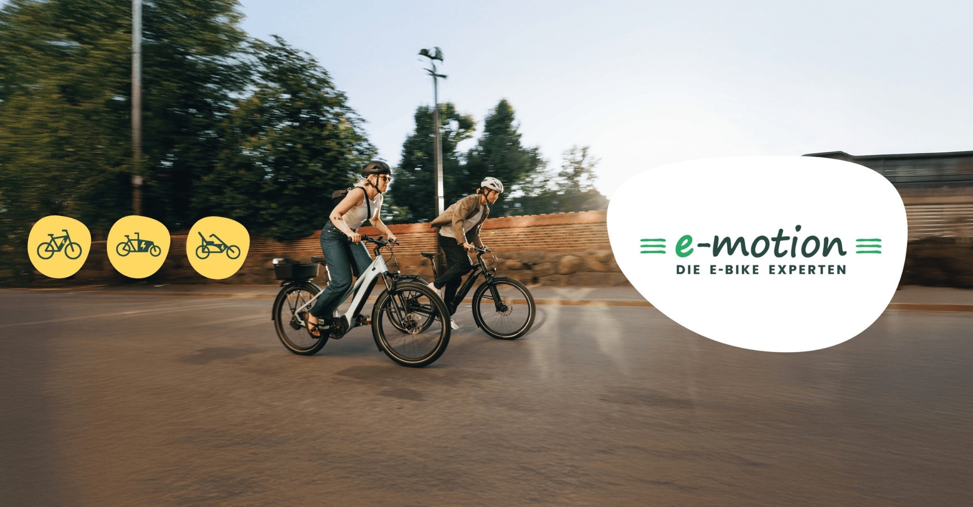 Zwei Personen auf e-Bikes, daneben das e-motion Logo und Icons der verschiedenen e-Bike Typen
