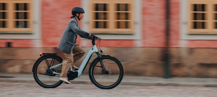 Mann fährt E-Bike vor historischem Gebäude
