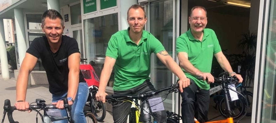 Drei Männer auf Fahrrädern vor einem Geschäft in Wien